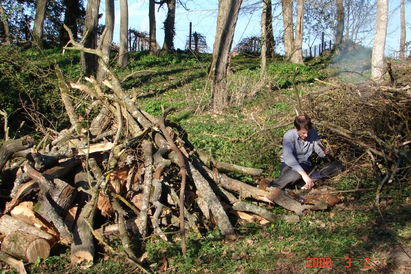 A pile of limbs to be sorted and cut.  Joe ignites a burning pile. 