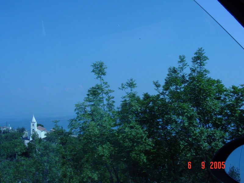 A church steeple in a small village is glimpsed through the scrub on the side of the road.